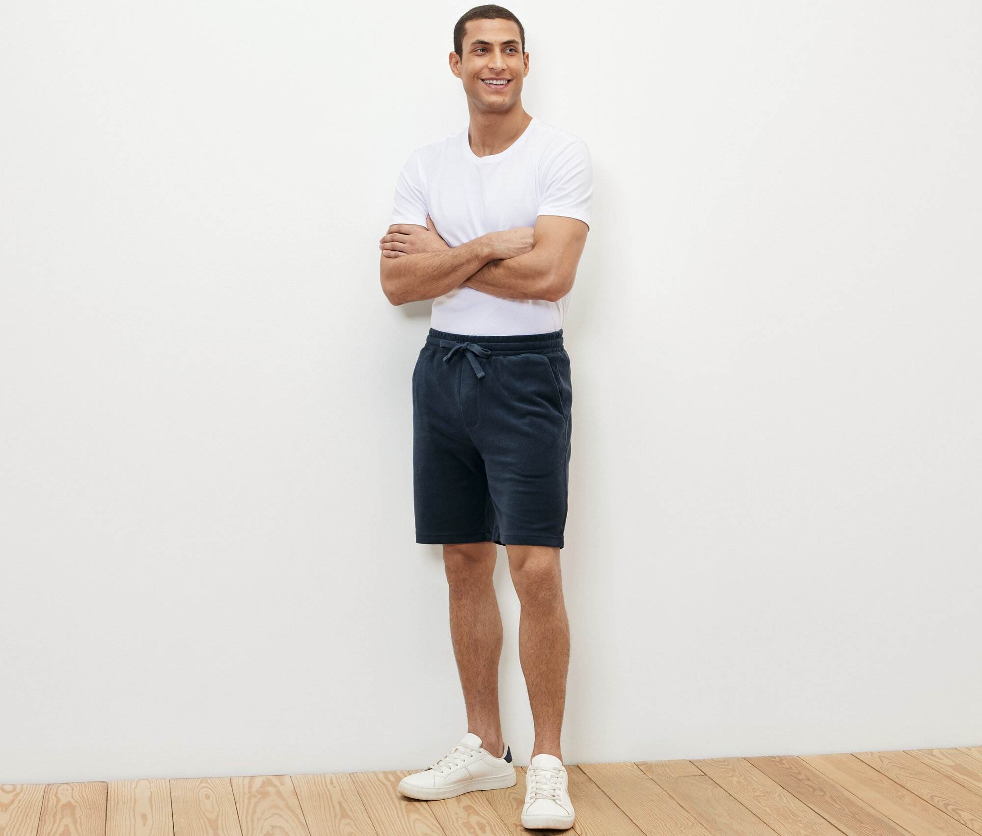 Mann steht mit verschränkten Armen und trägt blaue Frottee-Shorts.