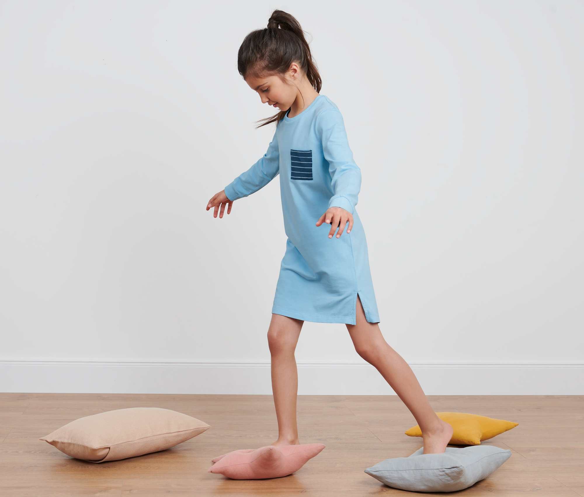 Mädchen balanciert in einem Mädchen-Nachthemd auf Kissen.