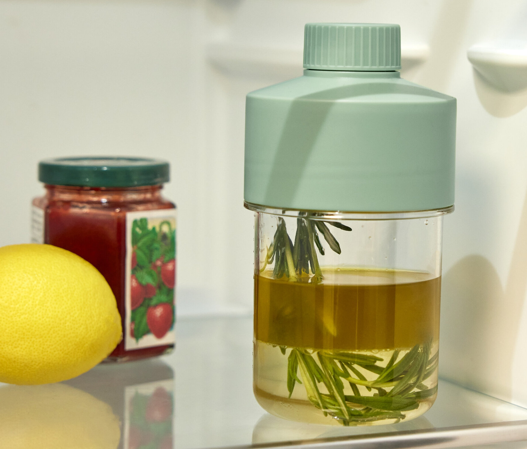 Im Kühlschrank stehen eine Dressingflasche, ein Marmeladenglas und eine Zitrone.