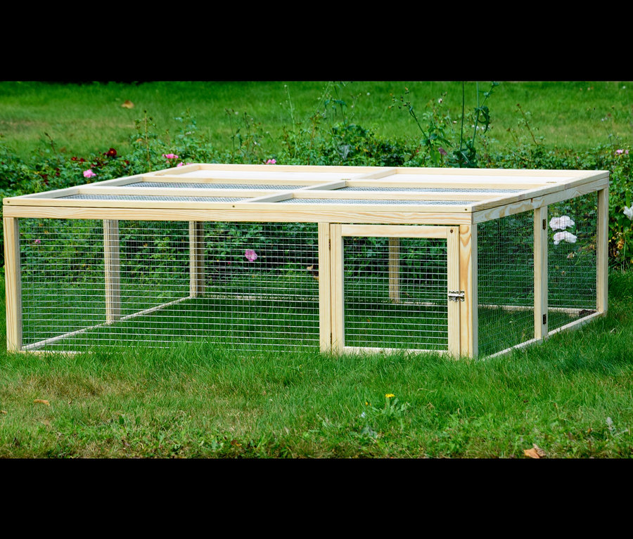 Dobar Freilaufgehege aus Holz steht auf einer Wiese.