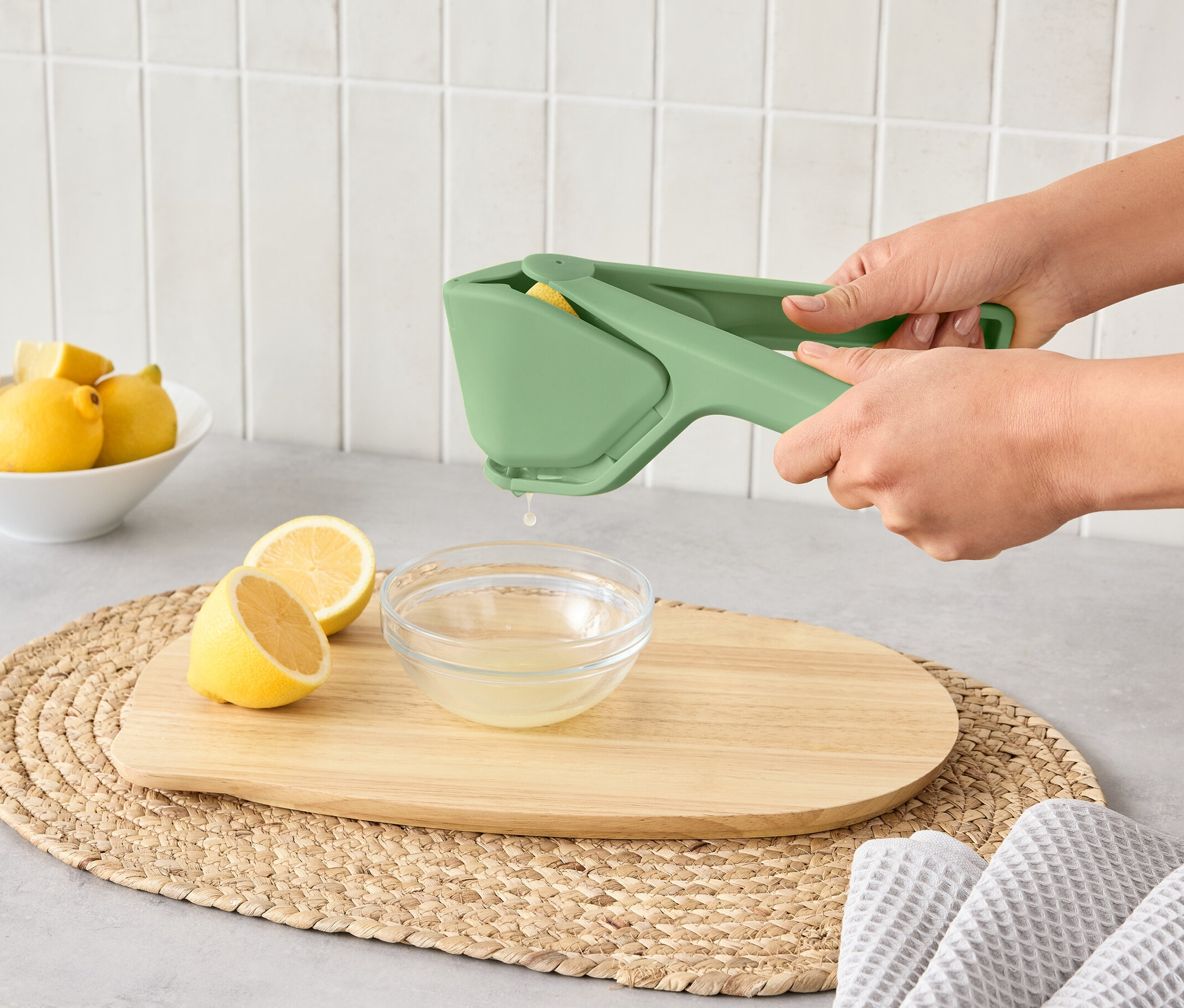 Frau presst Zitrone mit Platzspar-Zitruspresse in eine Schüssel.