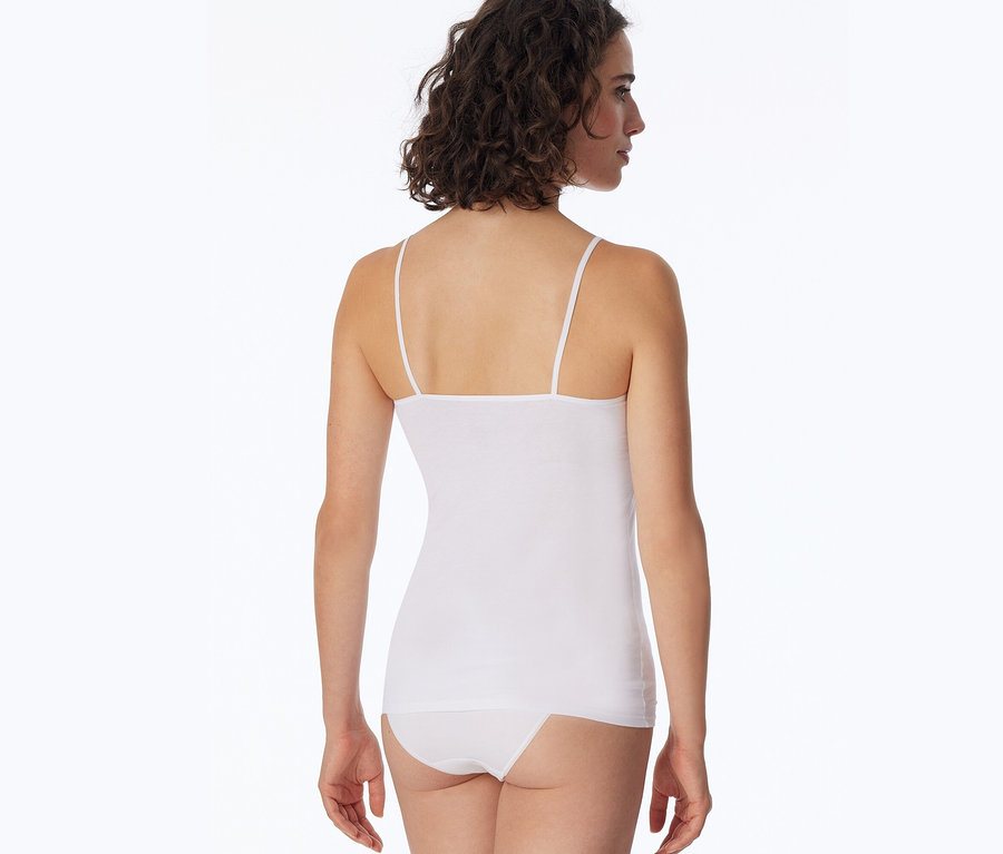 Rückansicht einer Frau mit braunen, lockigen Haaren, die ein weißes SCHIESSER Top und einen weißen Slip trägt.