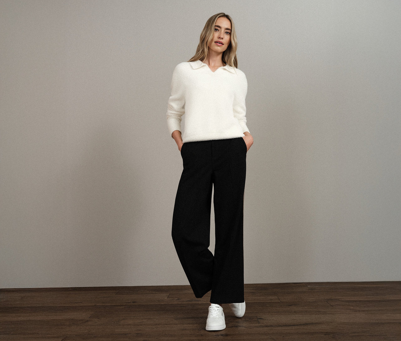Frau trägt einen weißen Street One Strickpullover mit Polokragen, schwarze Hose und weiße Turnschuhe.