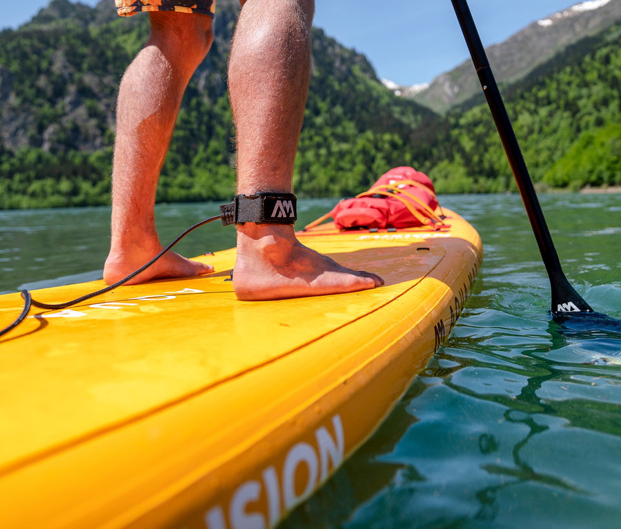 Mann steht auf gelbem Aqua Marina SUP Board »Fusion« 10'10" auf einem See.