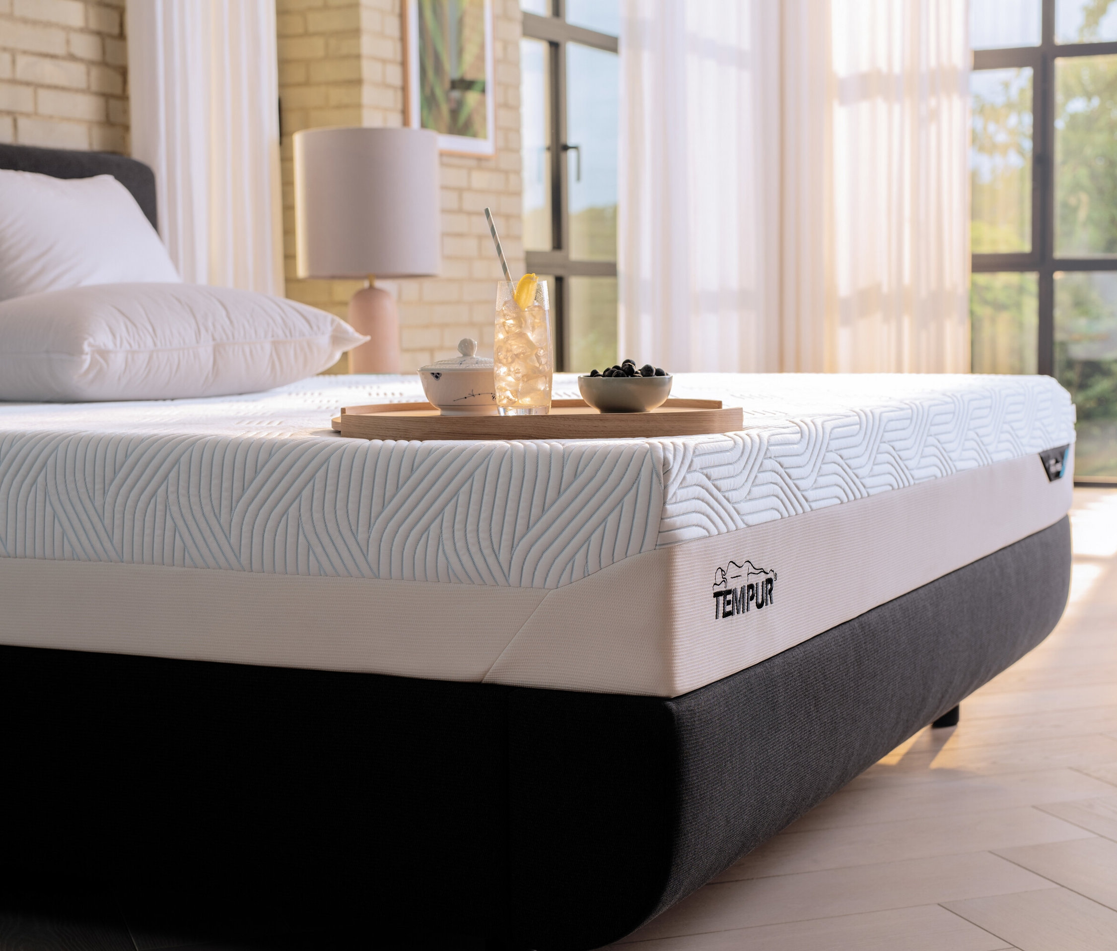 Eine Tempur Matratze Prima liegt auf einem Bett mit einem Getränk und Snacks auf einem Tablett.