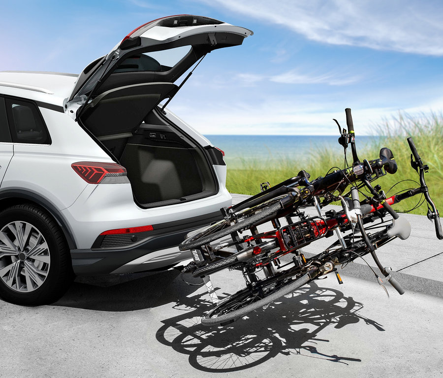 Weißes Auto mit geöffnetem Kofferraum. Am Auto ist ein EAL Fahrradträger »FINCH« für 3 Fahrräder montiert.