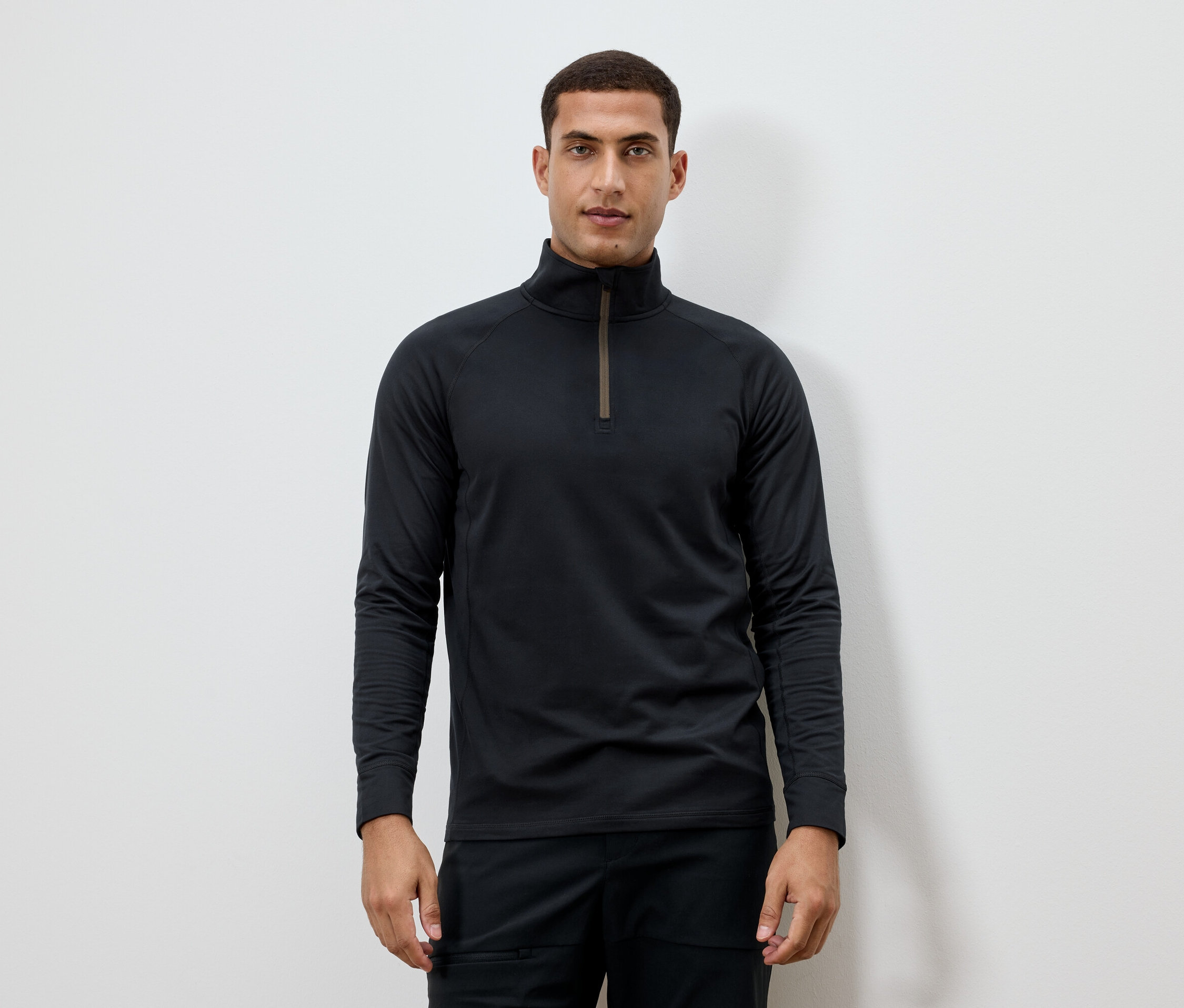 Mann trägt ein schwarzes Langarmshirt mit Reißverschluss am Hals.
