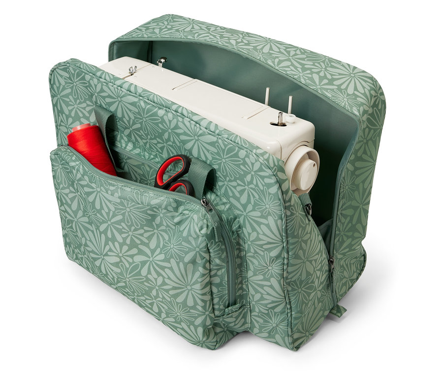 Geöffnete Nähmaschinentasche mit Blumenmuster, darin eine Nähmaschine, eine Spule rotes Garn und eine Schere.