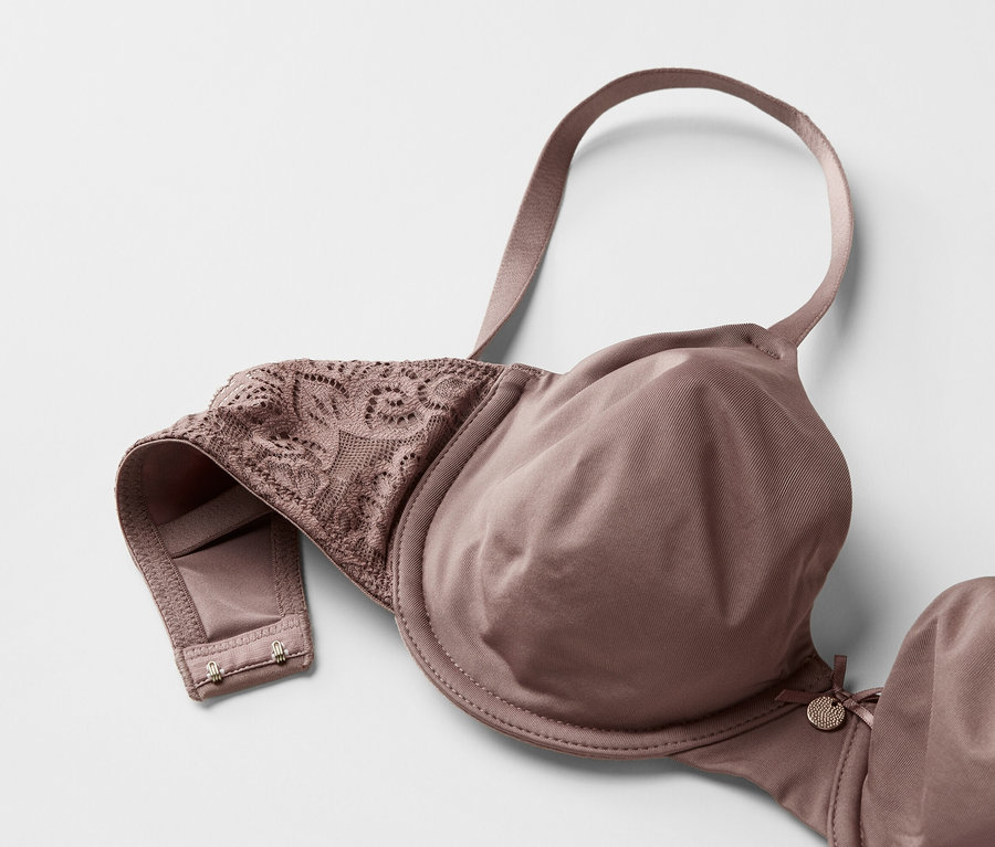 Nahaufnahme eines BHs in Malve mit Spitzenverzierung auf weißem Hintergrund.