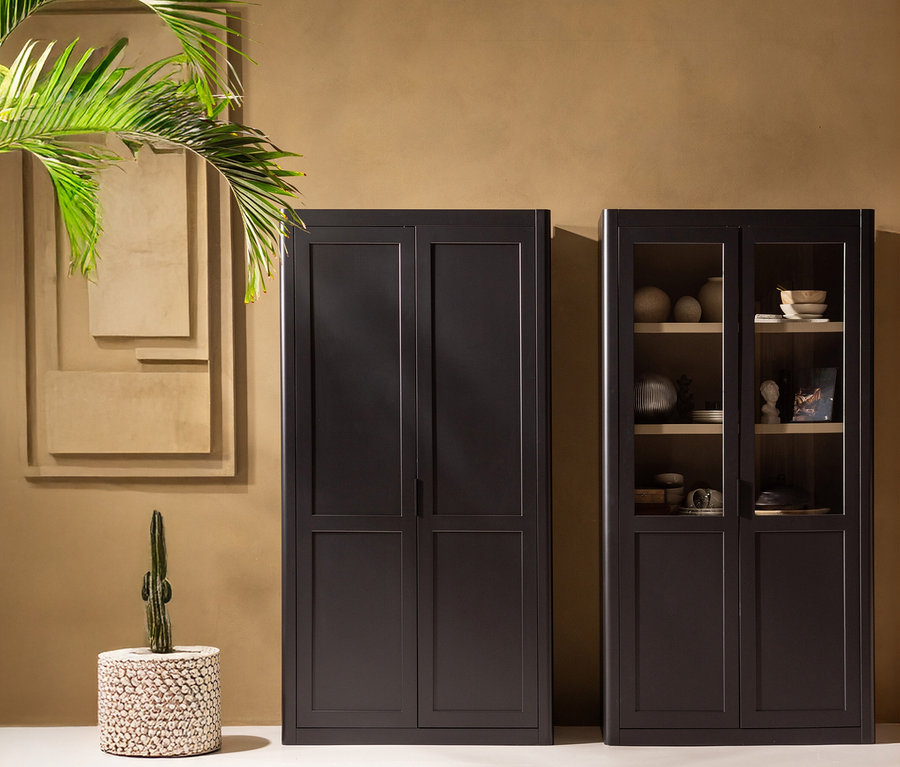 Zwei dunkle Schränke stehen vor einer beigen Wand, dekoriert mit einem abstrakten Bild und einer Pflanze.