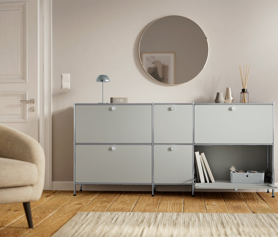 Grauer Schrank mit sechs Fächern steht neben einer Tür und einem Sessel.