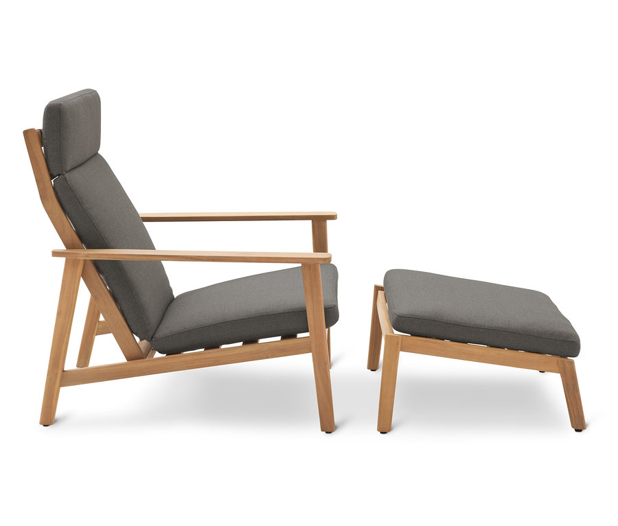 Ein grauer Sessel mit Holzrahmen steht neben einem grauen Hocker.