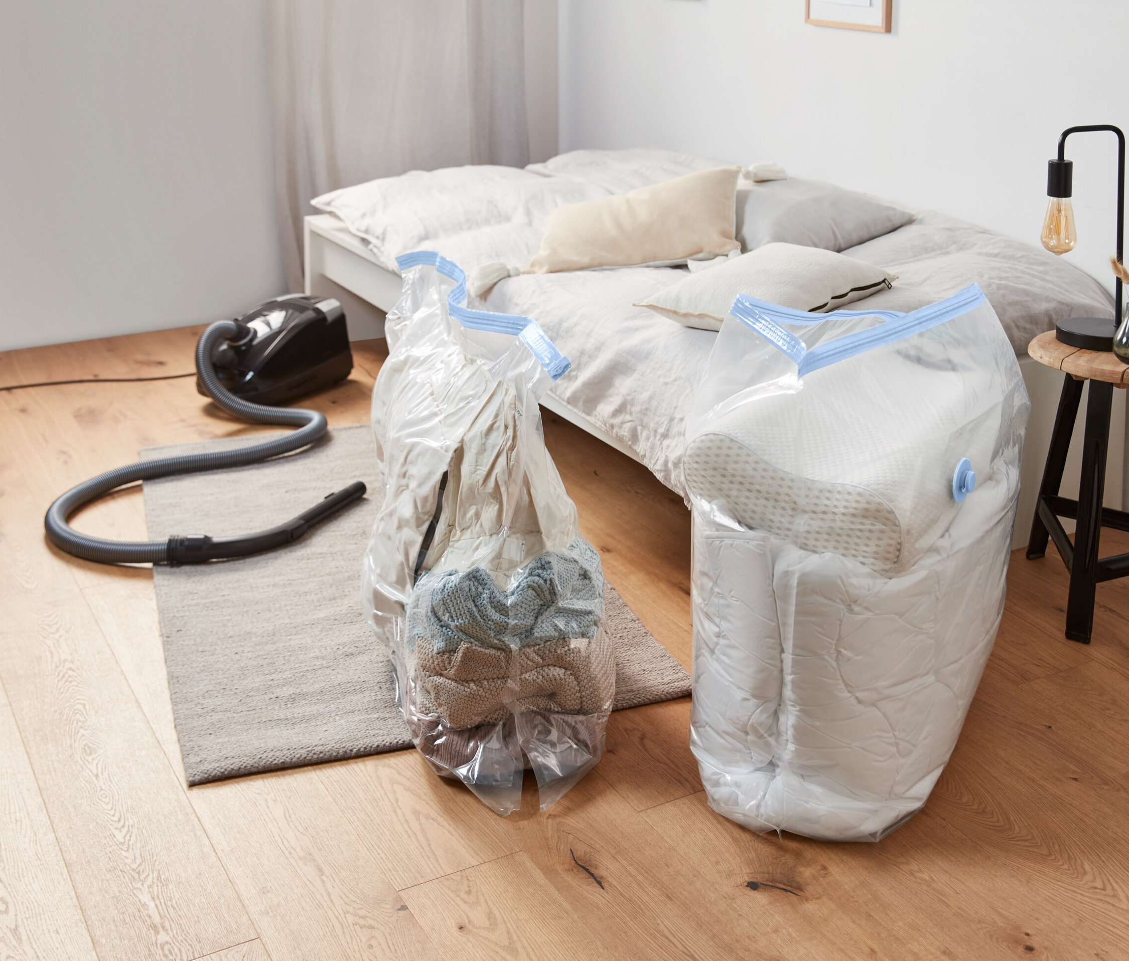 Zwei Vakuum-Aufbewahrungsbeutel, Würfel, liegen auf dem Boden neben einem Staubsauger.