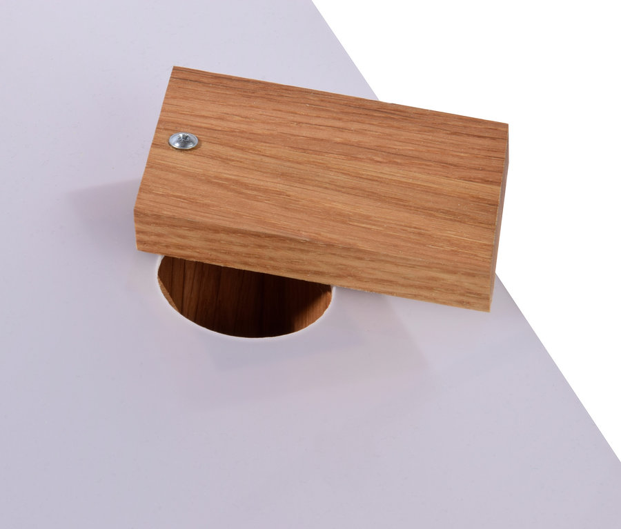 Detailaufnahme einer weißen Tischplatte mit einer Öffnung, über der ein Holzelement platziert ist, möglicherweise ein Design-Vogelhaus »Futura I«.