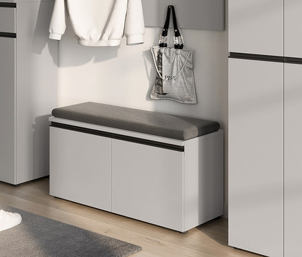 Eine graue gepolsterte Schuhbank »Vik« steht in einer Ecke neben weißen Schränken.