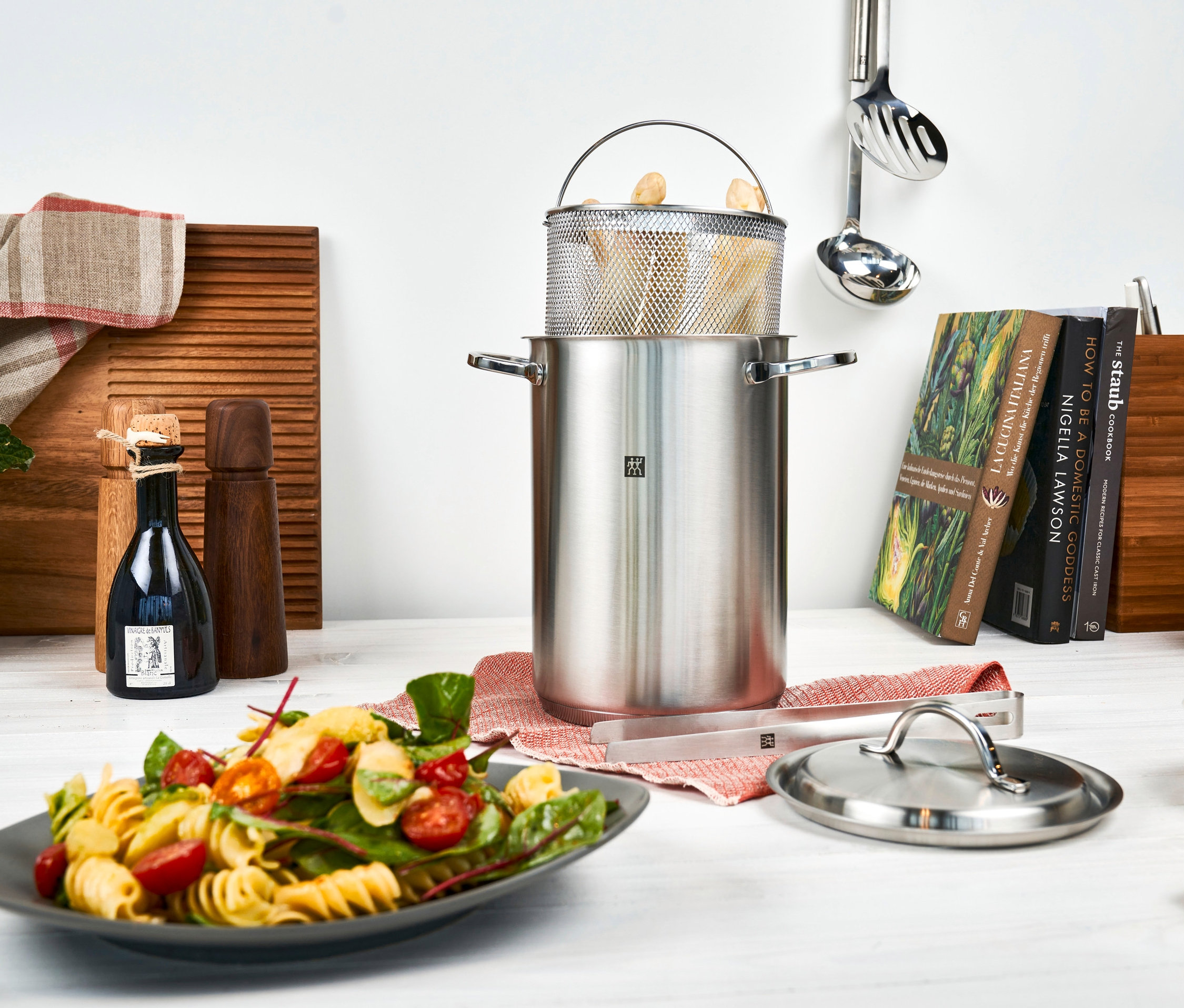 Ein ZWILLING Spargel-/Nudeltopf »Twin Specials« aus Edelstahl steht auf einem Tisch neben einem Teller mit Nudelsalat.