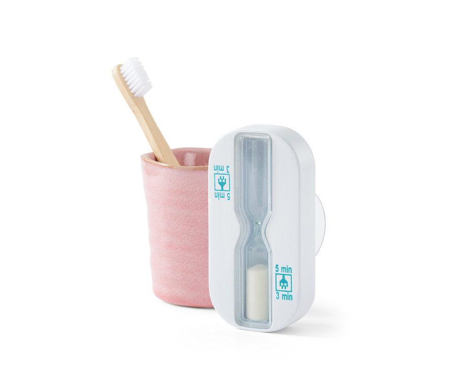 Bambuszahnbürste in rosa Becher neben Dusch-Sanduhr.