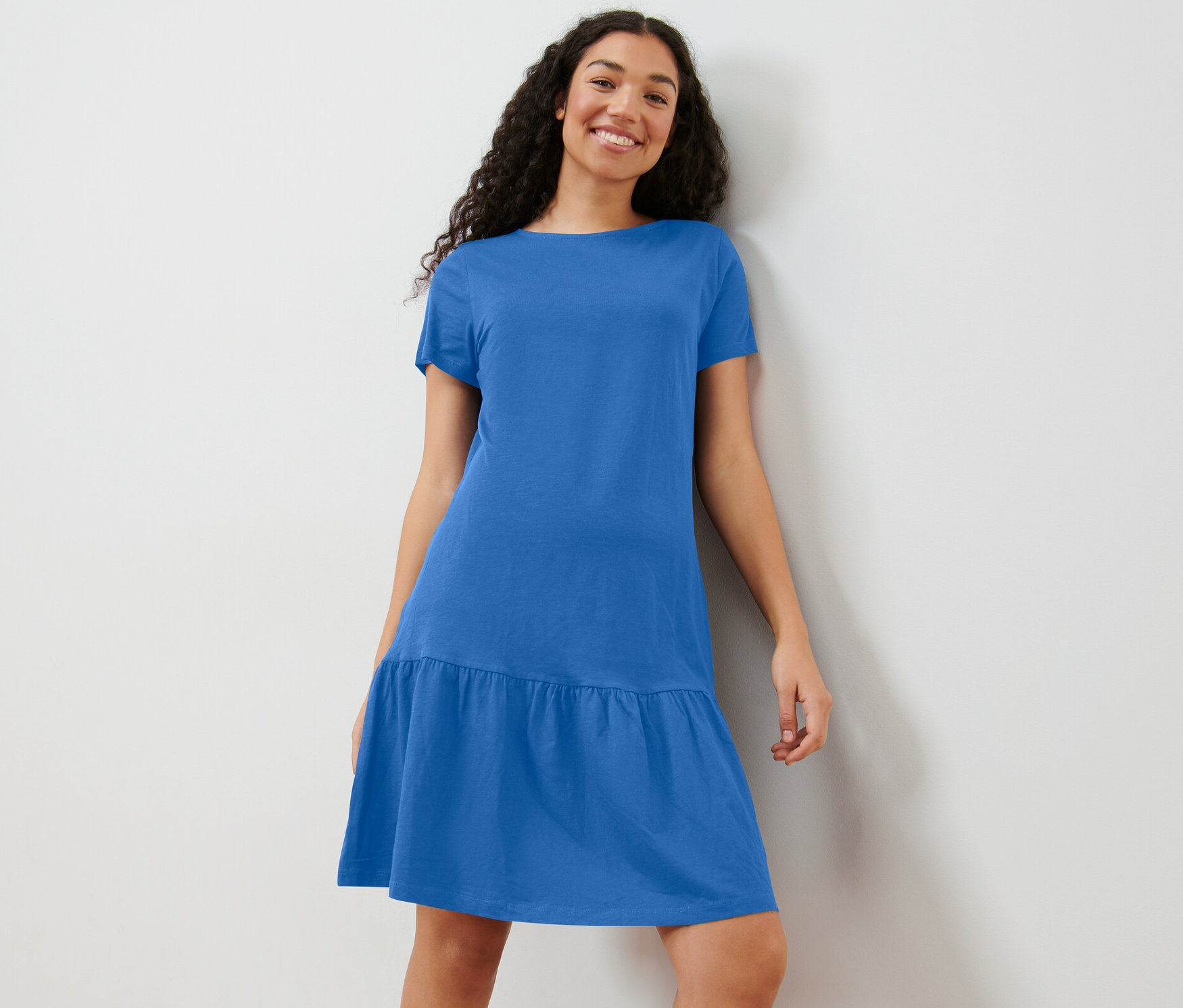 Frau posiert in kobaltblauem Jerseykleid mit Volant.