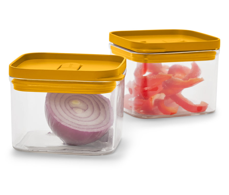 Zwei durchsichtige, quadratische Behälter mit senfgelben Deckeln. Einer mit einer halben roten Zwiebel, der andere mit geschnittener roter Paprika.