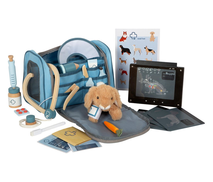 Ein 'small foot Tierarzt-Tasche mit Hase' Set liegt auf einem Tisch, inklusive Hasen Stofftier, Spielzeugspritze, Stethoskop und Röntgenbildern.