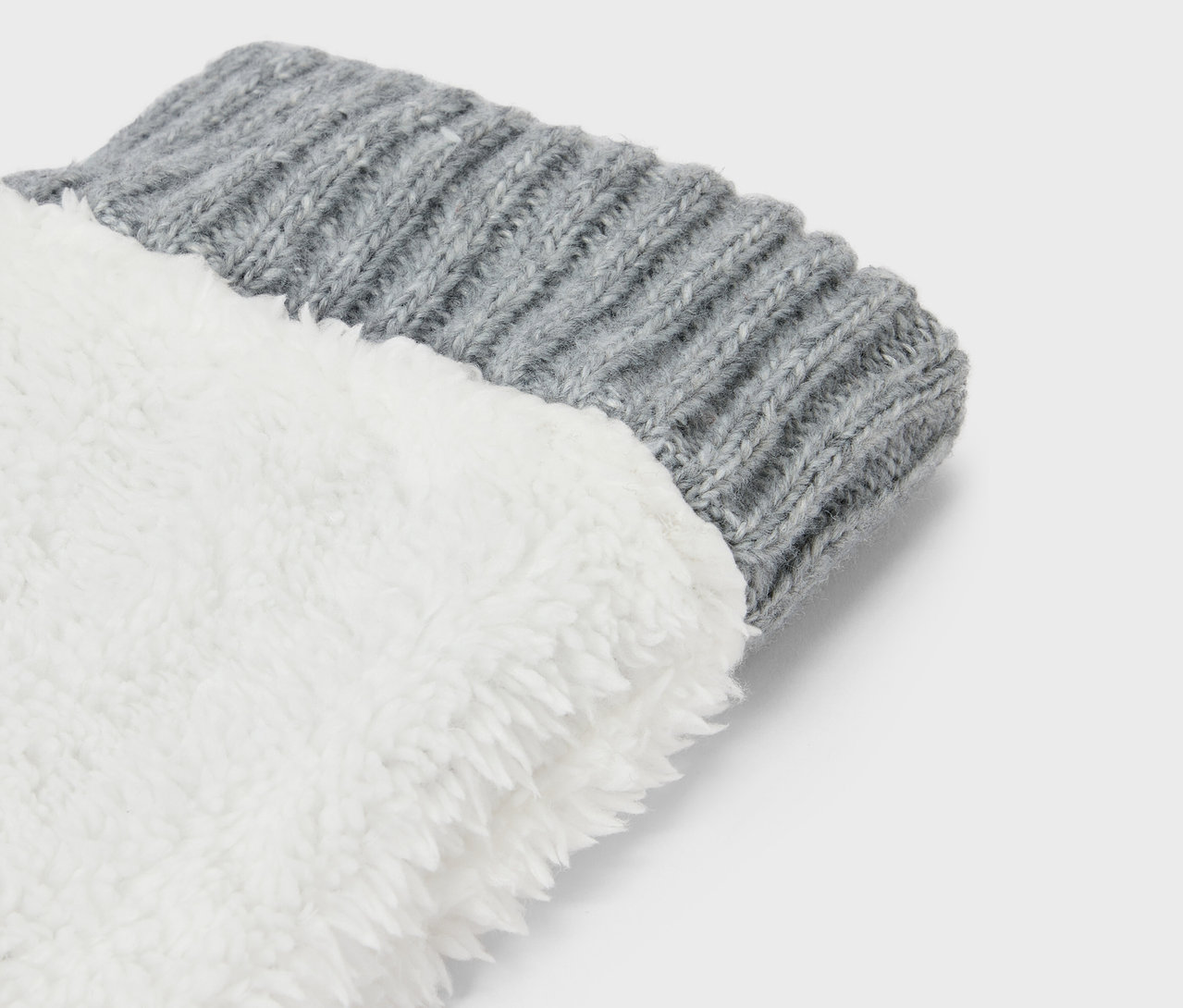 Detailaufnahme eines grauen Strickbündchens einer Socke mit weißem, flauschigem Futter.