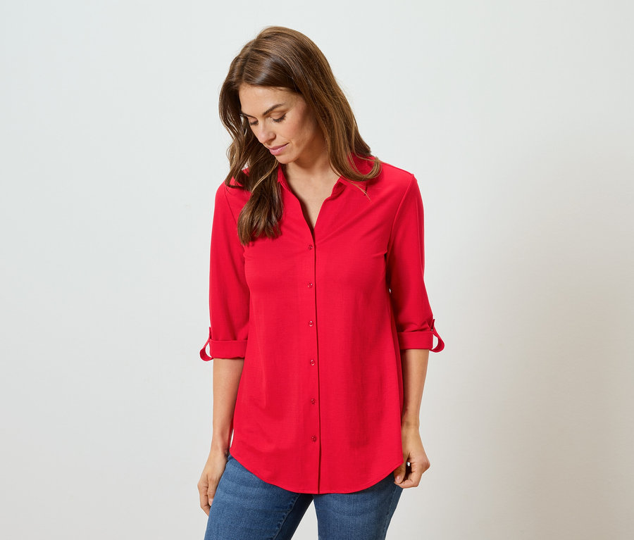 Frau trägt ein rotes Hemd und blaue Jeans.