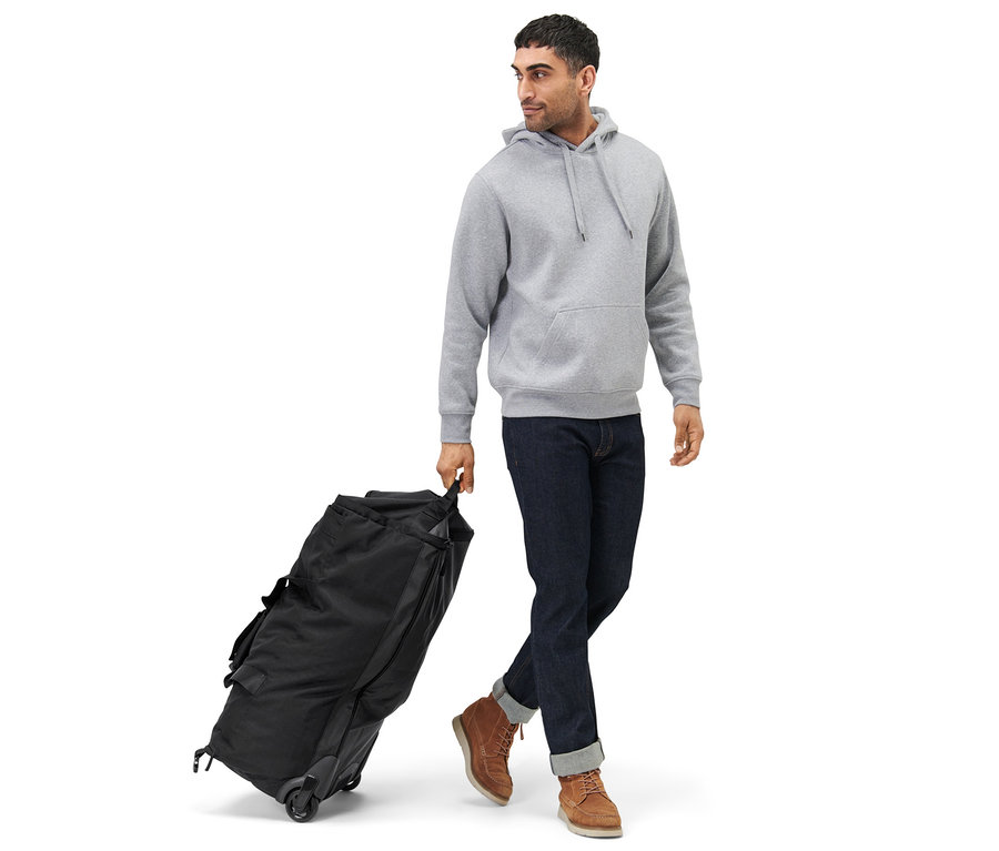 Mann zieht eine schwarze Rollentasche mit Rucksackfunktion.