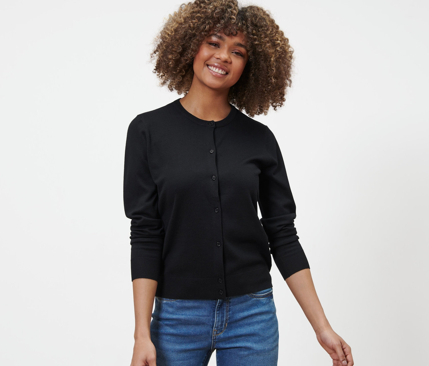 Frau trägt einen schwarzen Feinstrick-Cardigan und Jeans.
