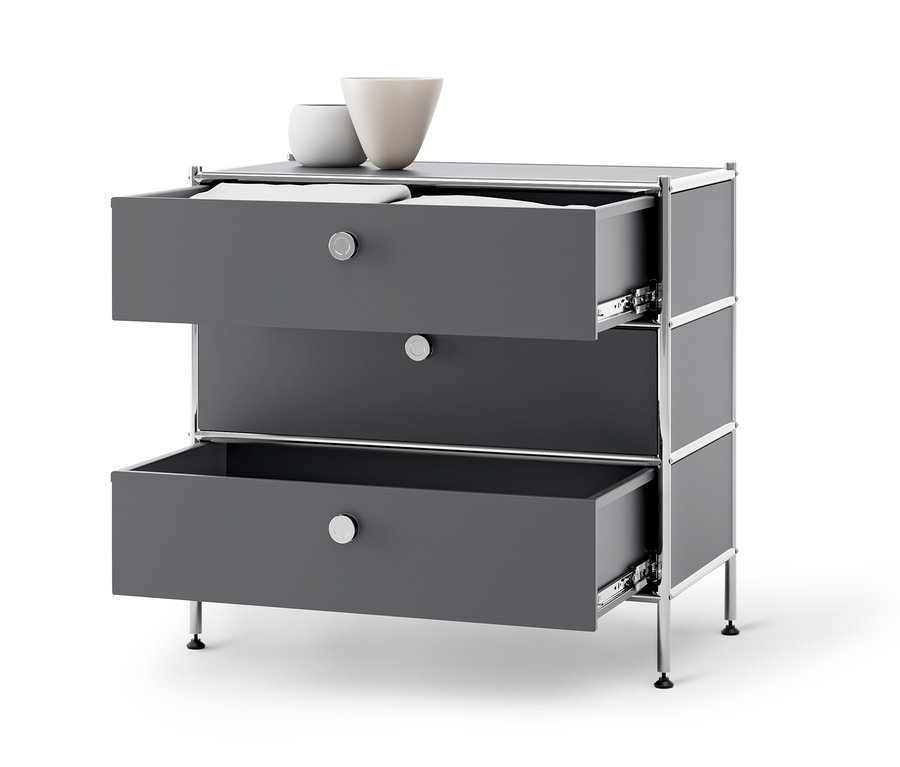 Eine graue Kommode Metall »CN3« mit drei Schubladen, von denen zwei geöffnet sind. Auf der Kommode stehen zwei Vasen.
