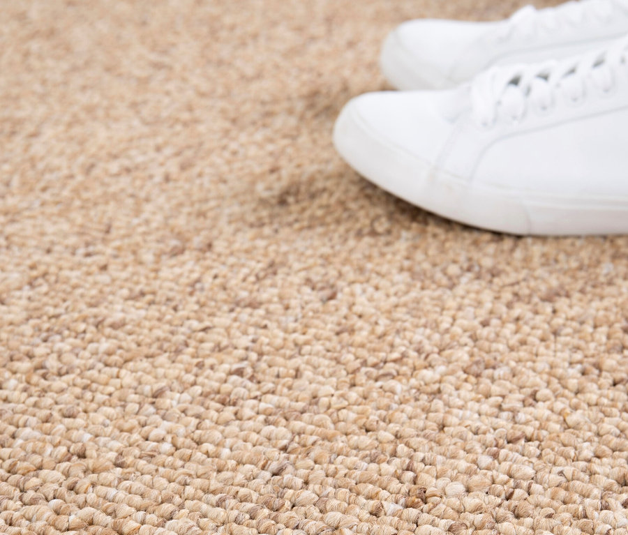 Nahaufnahme eines Sisalteppichs »Lino« mit weißen Schuhen im oberen Bereich.