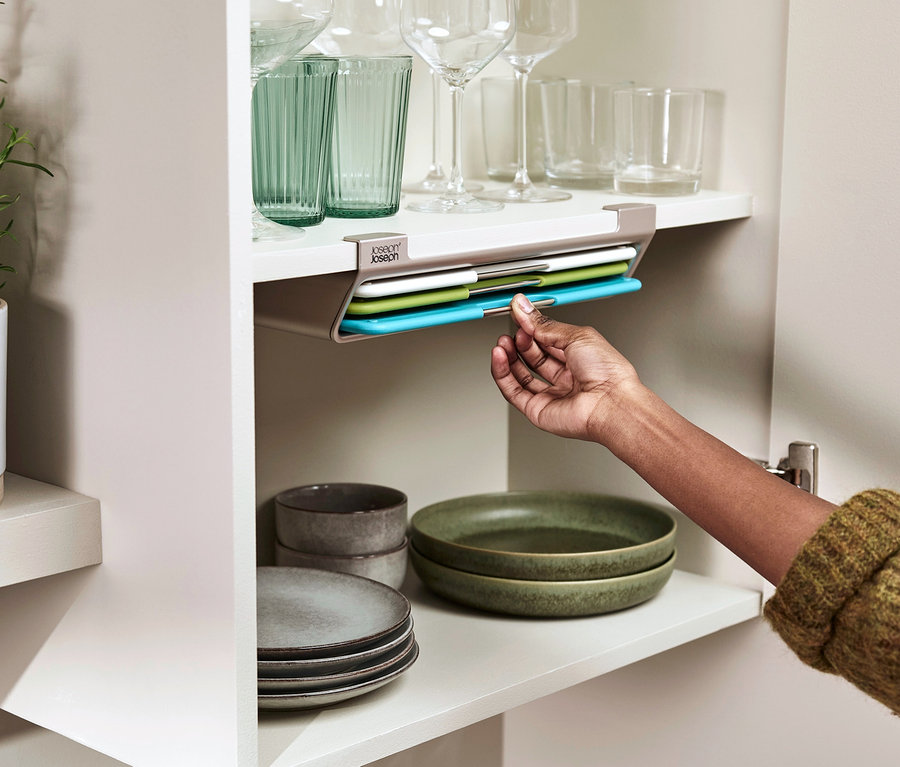 Eine Hand entnimmt ein farbiges Joseph Joseph »Folio Slim« Schneidebrett aus einem Schrank.