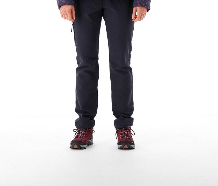 Eine Frau steht und trägt eine schwarze Mütze, eine Jacke und eine CMP Damenhose aus Stretch-Polyester.