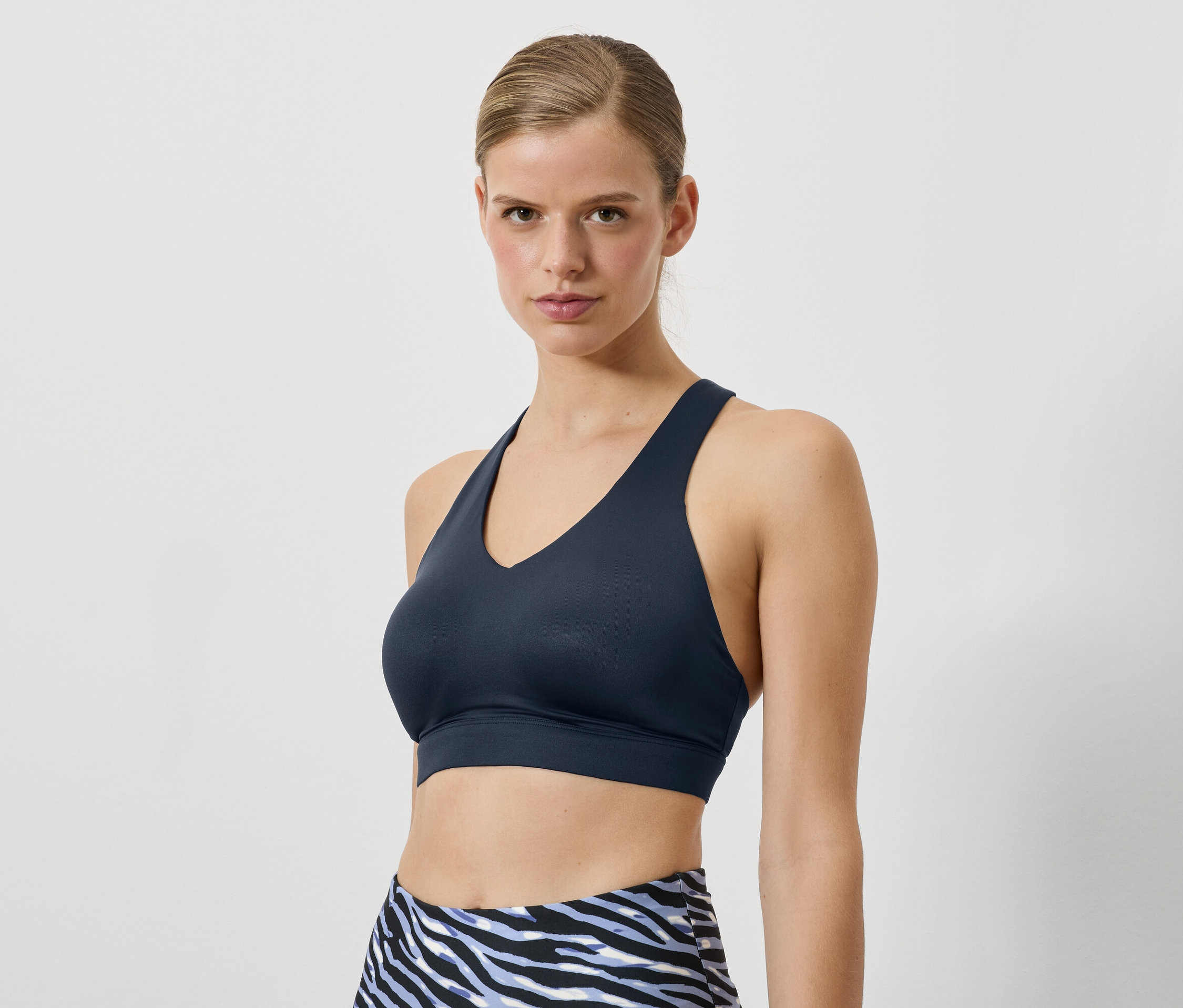 Frau trägt einen dunkelblauen Sport-BH und Leggings mit Tiermuster.