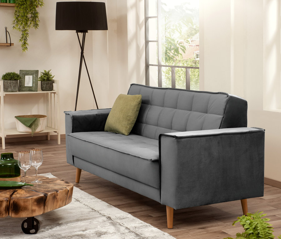Graues Max Winzer® 2-Sitzer-Sofa »Jolene« mit olivefarbenem Kissen in einem Wohnzimmer.
