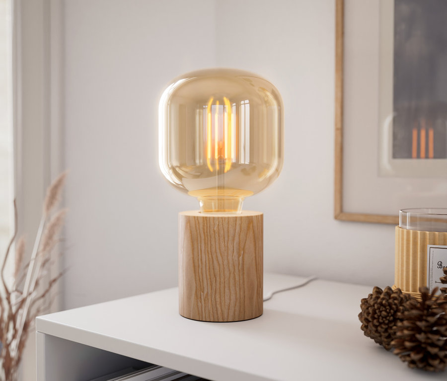 Tischleuchte aus Holz steht auf einem weißen Regal neben einem Tannenzapfen.