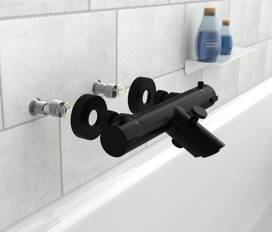 Eine schwarze Thermostat-Wannenfüllarmatur »London« ist an weißen Fliesen über einer weißen Badewanne montiert.