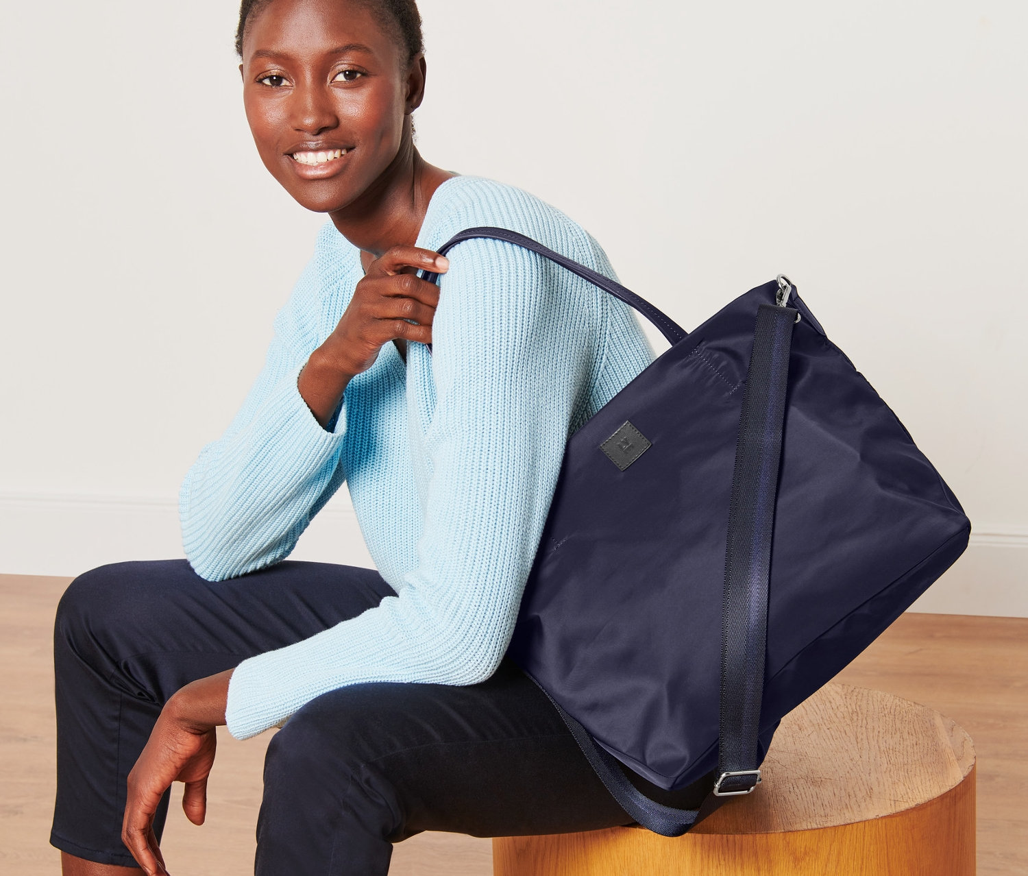 Frau sitzt mit Shopper über der Schulter.