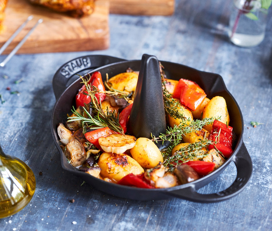 Gebratenes Hähnchen mit Kartoffeln und Paprika im schwarzen STAUB Hähnchen-Bräter.