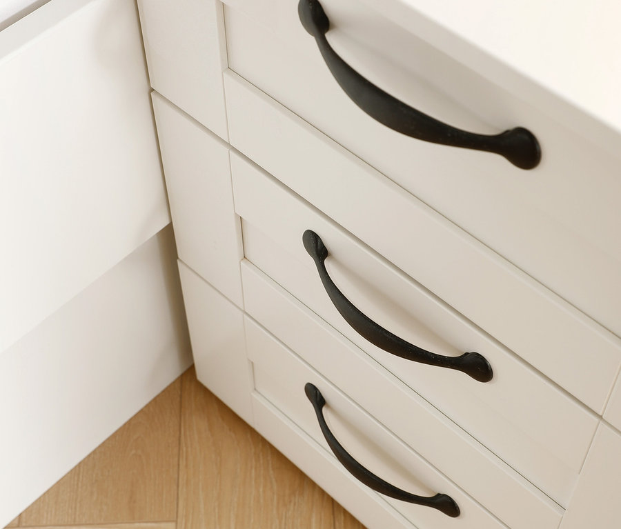 Detailansicht eines weißen rauch »Cottage« Nachttischs mit drei Schubladen und schwarzen Griffen.