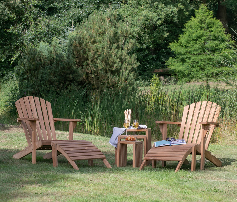 Zwei DeVries Adirondack Sessel inklusive Auflage auf einer Wiese mit Tisch, Getränken und einer Decke in einem Korb.