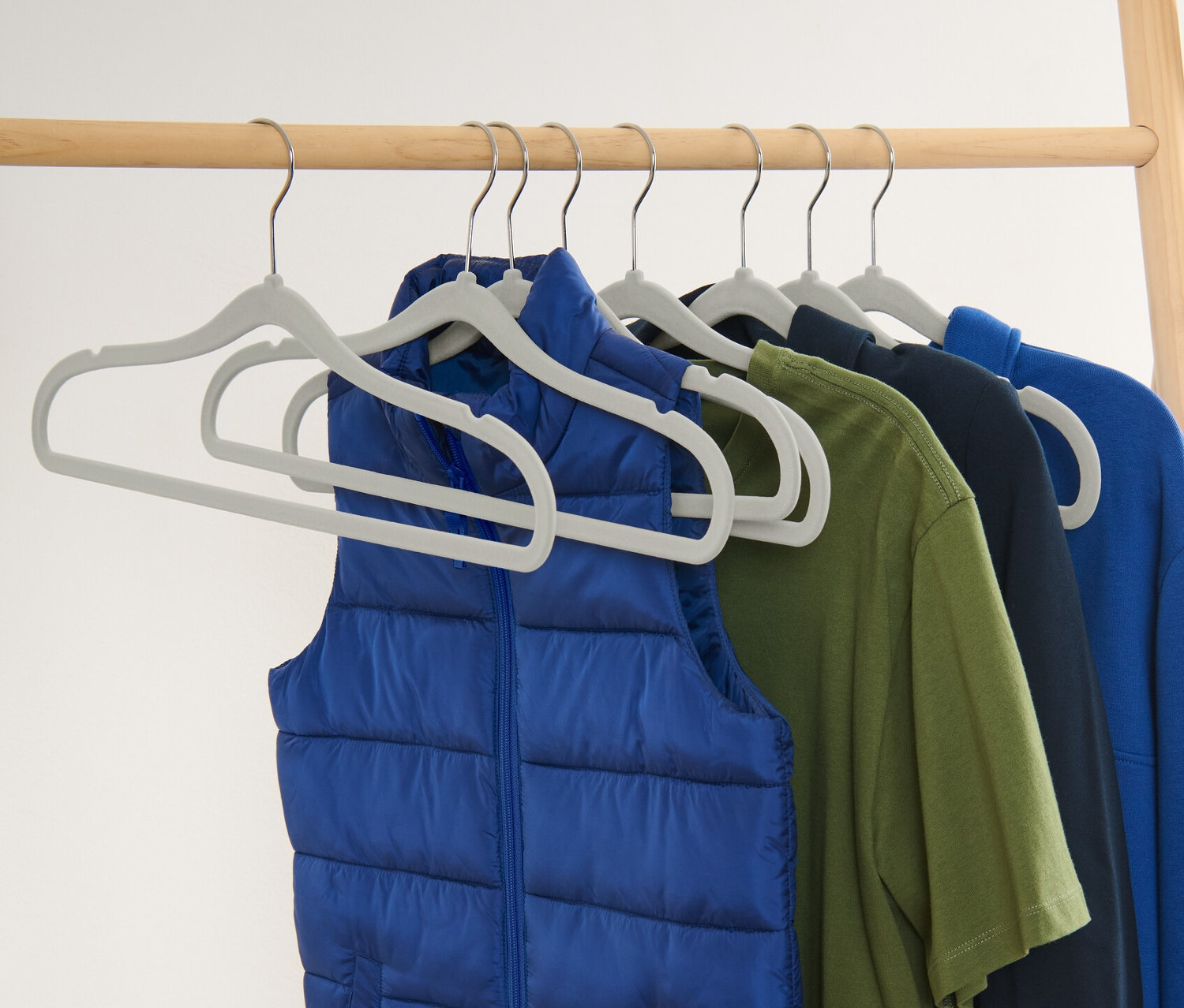 Eine blaue Weste und bunte Kleidungsstücke hängen an 8 extraschmalen Kleiderbügeln.