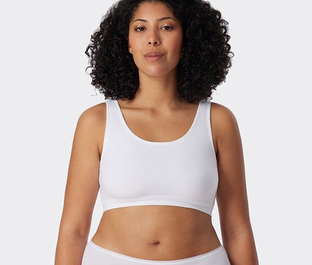 Frau trägt 2 SCHIESSER Bustiers mit Bio-Baumwolle, weiß und eine weisse Unterhose.