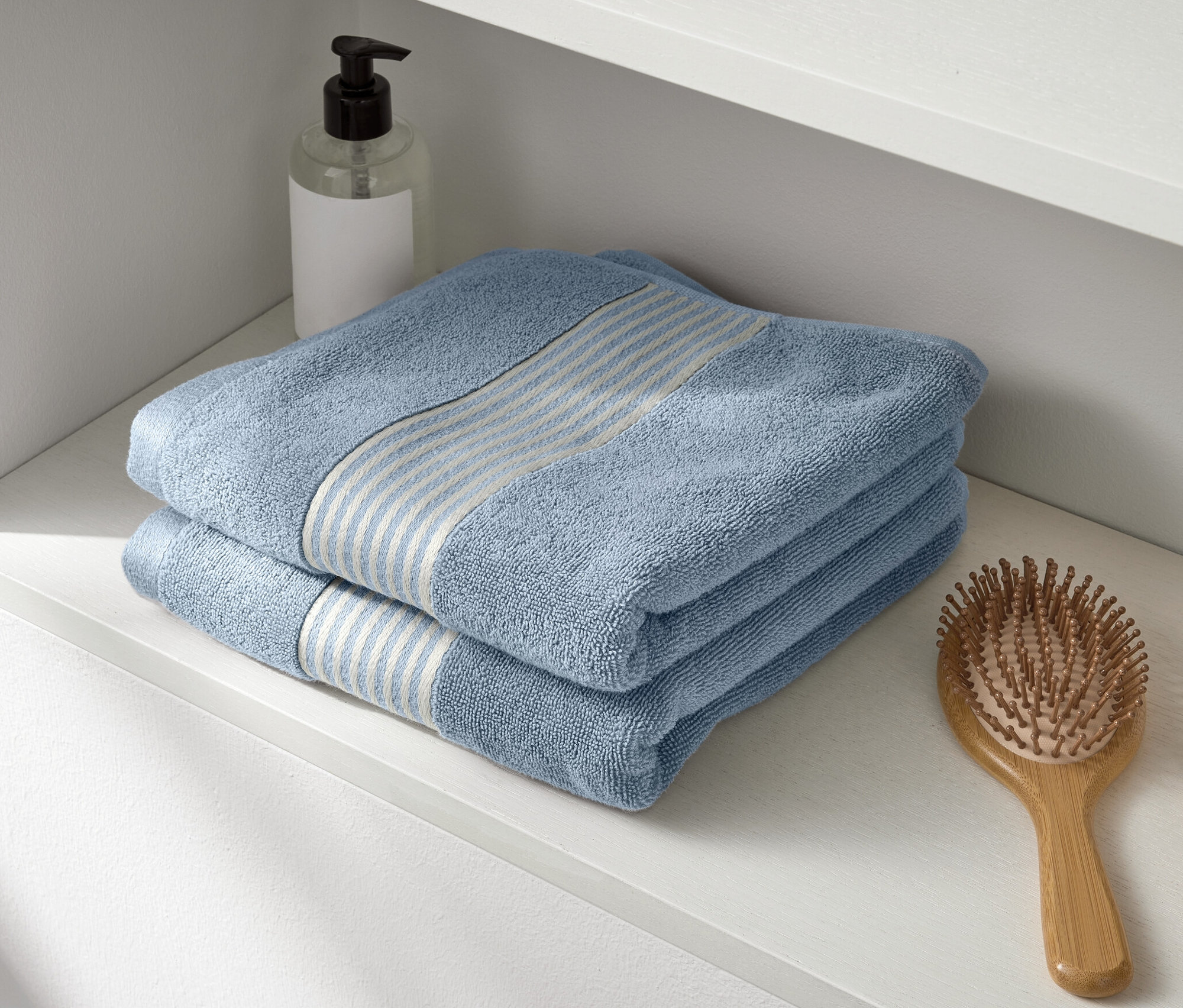 Auf einem weißen Regal liegen zwei blaue Premium-Handtücher.