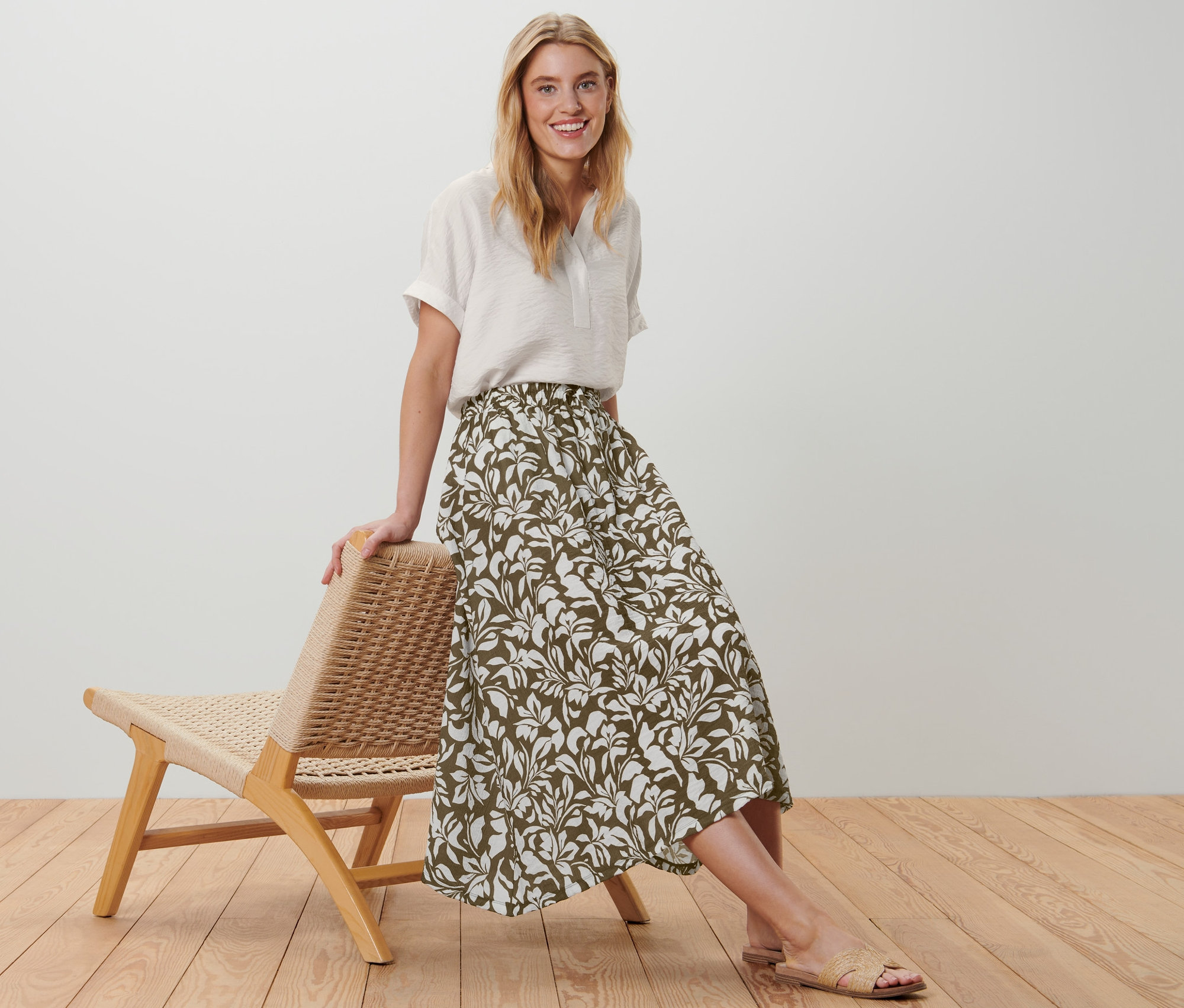 Frau posiert an einem Stuhl, sie trägt einen bedruckten Midi-Rock.