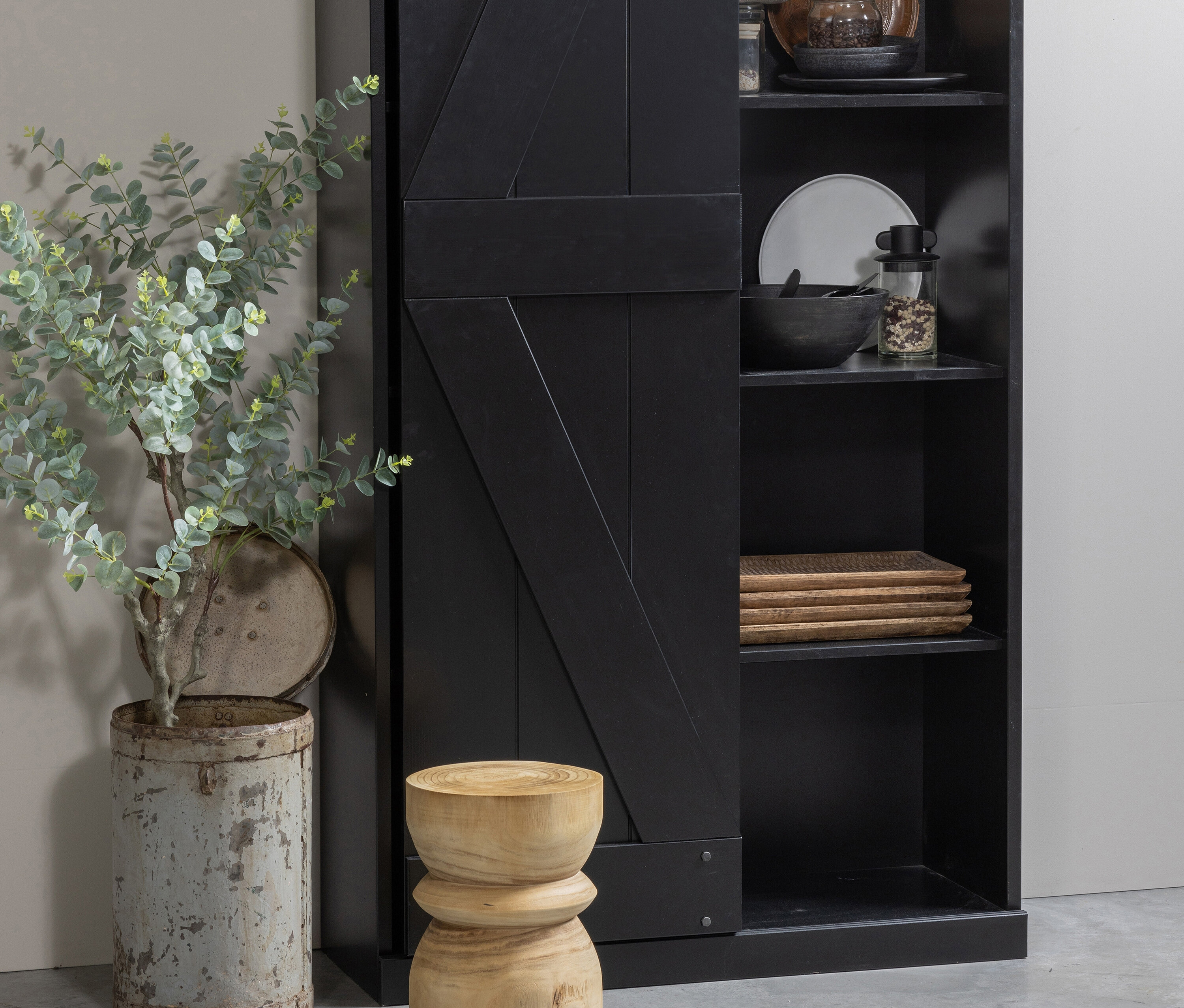 Dekoratives Interieur mit schwarzem Schrank, Pflanze in grauem Behälter und naturfarbenem Woood Hocker »Bikkel«.