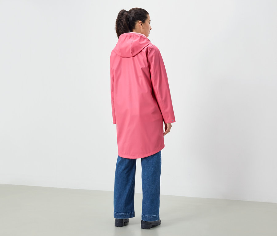 Eine Frau von hinten, die einen rosa Regenmantel mit Kapuze und blaue Jeans trägt.
