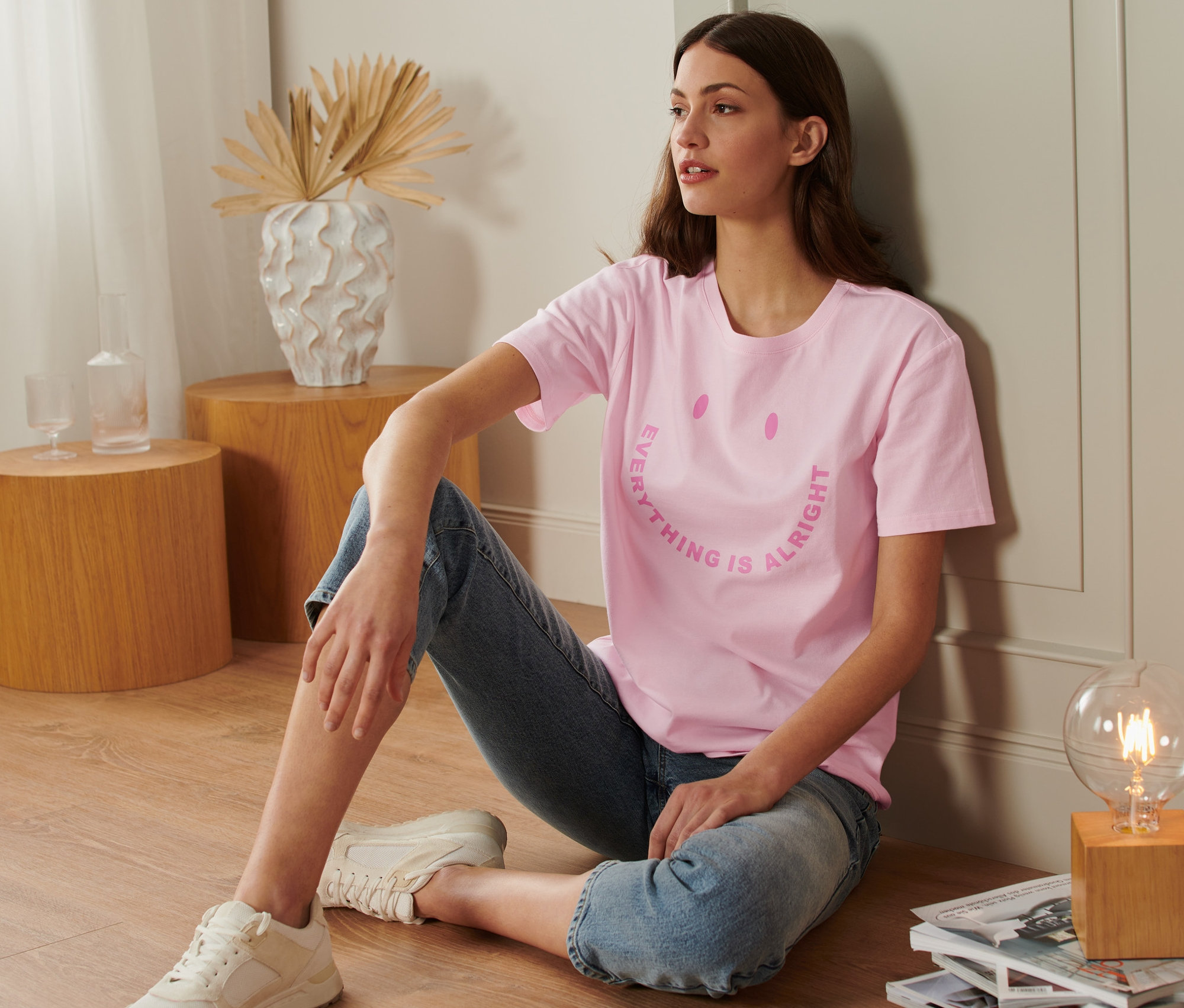 Frau sitzt auf dem Boden und trägt ein T-Shirt mit Statement-Print.