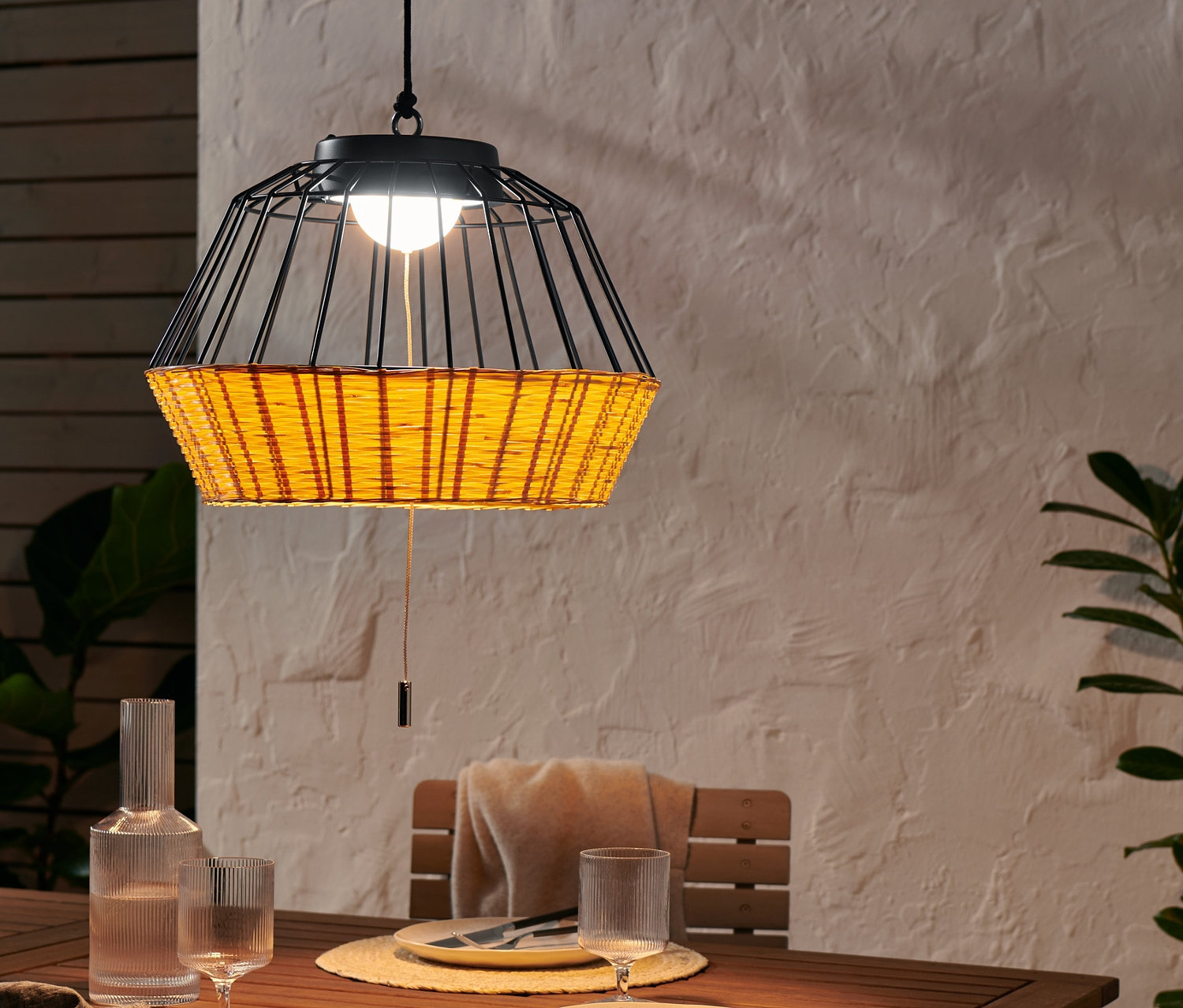 LED-Outdoor-Hängeleuchte hängt über einem Tisch. Auf dem Tisch stehen Gedecke, Teller, Besteck, Gläser und eine Wasserkaraffe.