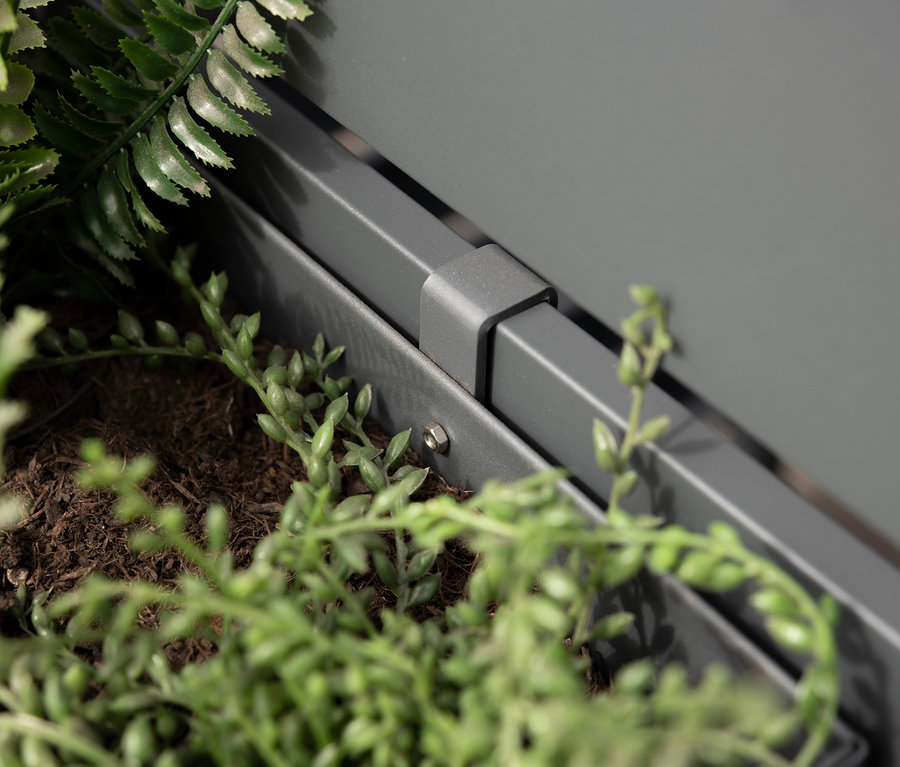 Detailaufnahme eines grauen Blumenkastens aus Stahl mit Pflanzen.