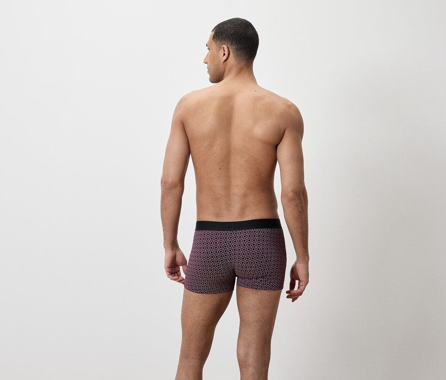 Mann von hinten, trägt violette Boxershorts mit geometrischem Muster.